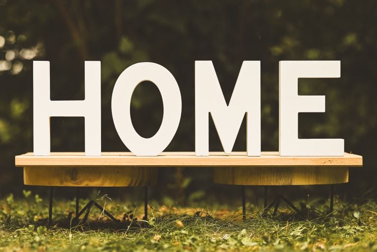 Artistic display of wooden letters spelling 'HOME' on a bench outdoors.