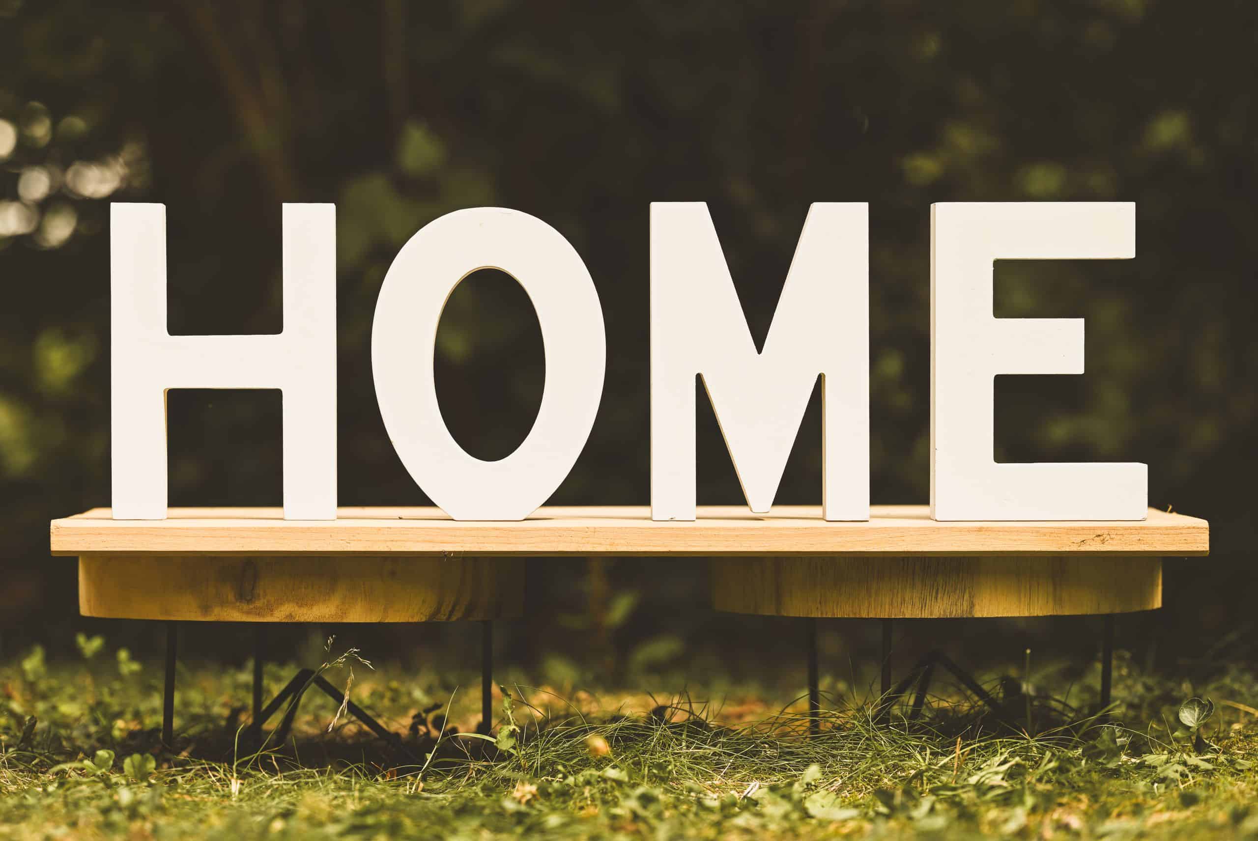 Artistic display of wooden letters spelling 'HOME' on a bench outdoors.