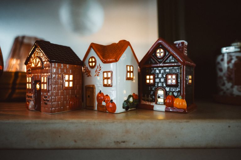 Cozy ceramic houses with lit windows, ideal for autumn home decoration. Features pumpkins and warm autumn colors.